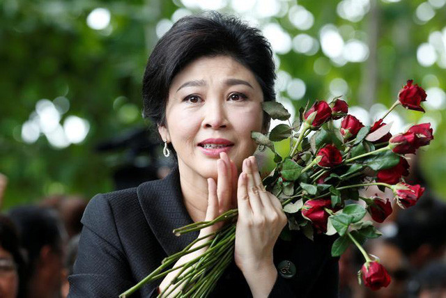 Cựu Thủ tướng Yingluck xúc động khi được nhận hoa từ người ủng hộ trong phiên tòa trước đó. (Ảnh: Reuters)