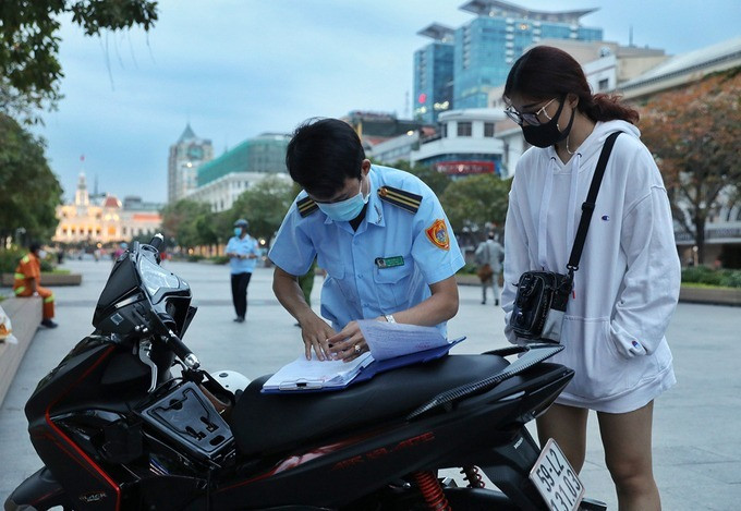 Đội trật tự đô thị phường Bến Nghé, quận 1, xử phạt người không đeo khẩu trang trên phố đi bộ Nguyễn Huệ, chiều 15/4. Ảnh: Quỳnh Trần.