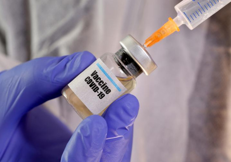 Một kỹ thuật viên đang cầm lọ thủy tinh nhỏ có nhãn dán Vaccine Covid-19 và một ống tiêm y tế trong một phòng thí nghiệm, ngày 10/4/2020. Ảnh: Reuters.