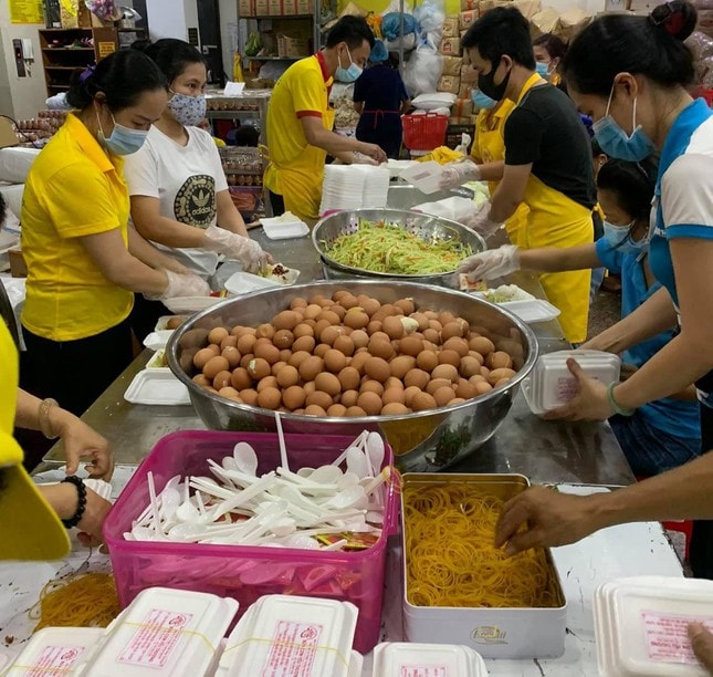 Tình nguyện viên chuẩn bị cho cơm vào hộp tại bếp ăn chùa Tường Nguyên.