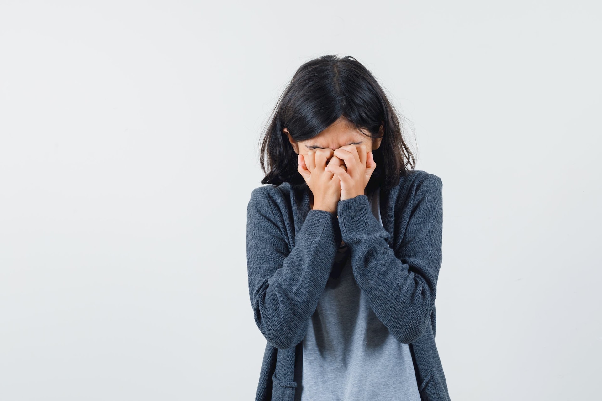 young-girl-covering-face-with-hands-light-gray-t-shirt-dark-grey-zip-front-hoodie-looking-sad.jpg
