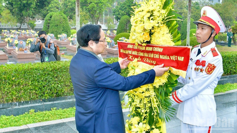 Thủ tướng Phạm Minh Chính chỉnh hoa trước khi thực hiện nghi lễ dâng hương, dâng hoa tưởng nhớ các Anh hùng liệt sĩ tại Nghĩa trang liệt sĩ quốc gia A1. (Ảnh: THANH GIANG) ndo_br_c4-7168.jpg