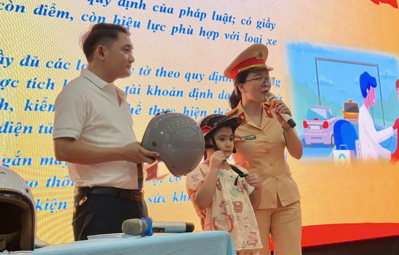 CSGT hướng dẫn học sinh cài quai mũ bảo hiểm đúng cách trong chương trình tuyên truyền an toàn giao thông.