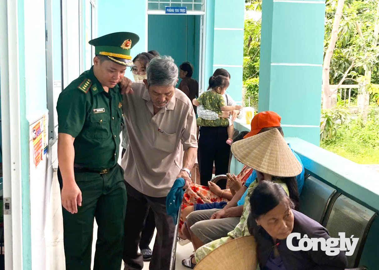 Cán bộ đồn Biên phòng Đất Mũi hỗ trợ người dân đi lại khó khăn được đến nơi khám mắt