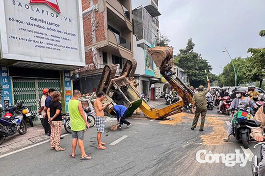 Xe múc 5 tấn lật ngửa ở TP.HCM