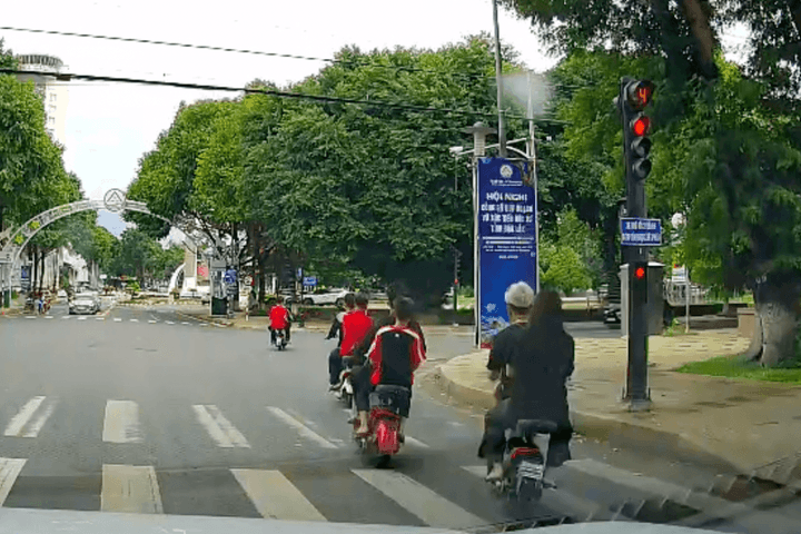 Nhóm học sinh đi xe điện vượt đèn đỏ, không đội mũ